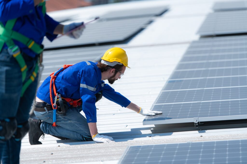 Both of technicians is installing solar panels on the roof of the warehouse